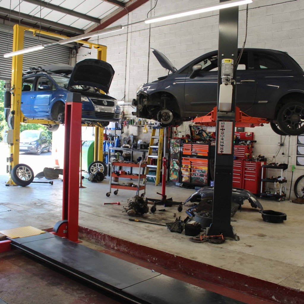 A car suspended in the air with a mechanic ready to work on it